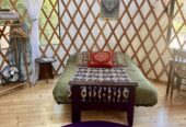 16’ round green Pacific Yurt with tiny fireplace